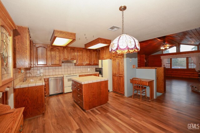 kitchen with stove, dishwasher, vaulted ceiling with beams, a kitchen island, and white fridge with ice dispenser