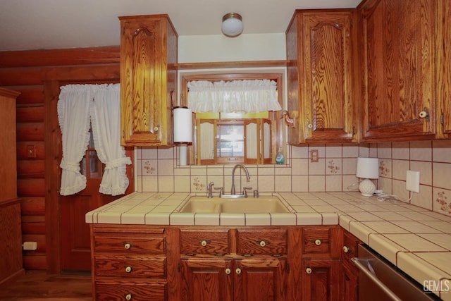 kitchen with dishwasher, tile countertops, tasteful backsplash, and sink