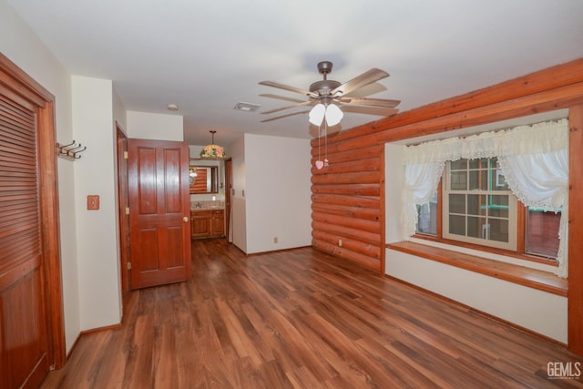 interior space with dark hardwood / wood-style floors, ceiling fan, and rustic walls