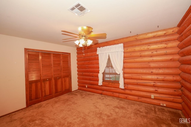 unfurnished bedroom featuring carpet floors, ceiling fan, a closet, and log walls