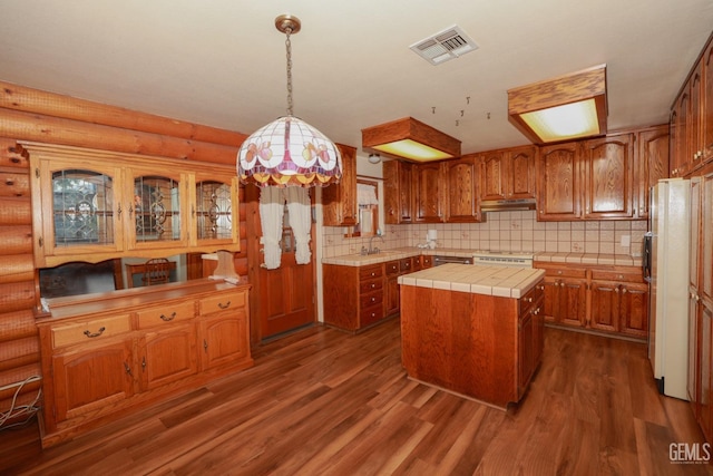 kitchen with rustic walls, dark hardwood / wood-style flooring, a kitchen island, and sink