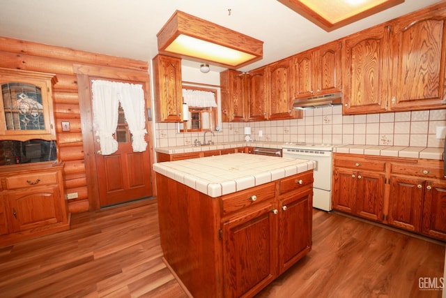 kitchen featuring rustic walls, tile countertops, stove, wood-type flooring, and a kitchen island