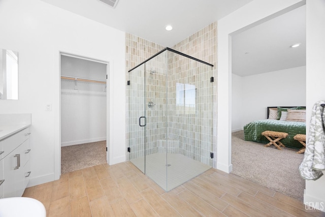 12914 Altair Ct, Bakersfield, CA 93314 - ensuite bathroom featuring connected bathroom, vanity, a spacious closet, wood finished floors, and a stall shower