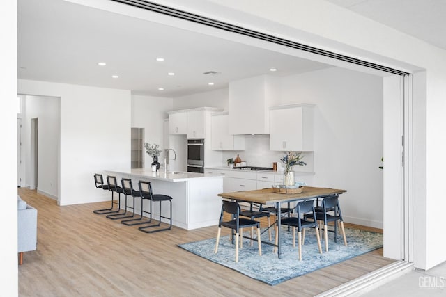 12914 Altair Ct, Bakersfield, CA 93314 - kitchen featuring light wood-type flooring, white cabinets, a kitchen island with sink, gas stovetop, and a sink