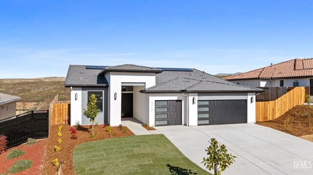 12914 Altair Ct, Bakersfield, CA 93314 - prairie-style house featuring solar panels, an attached garage, concrete driveway, fence, and stucco siding