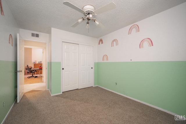 unfurnished bedroom with carpet flooring, a textured ceiling, a closet, and ceiling fan