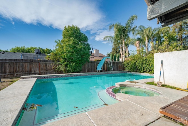 view of swimming pool featuring an in ground hot tub and a water slide