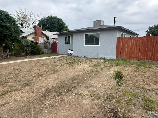 back of property featuring stucco siding and fence