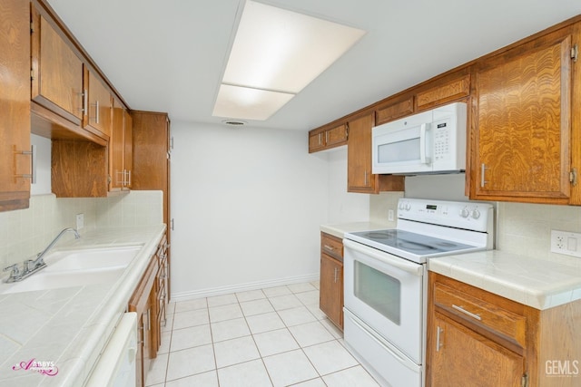 kitchen with light tile patterned flooring, sink, decorative backsplash, tile counters, and white appliances