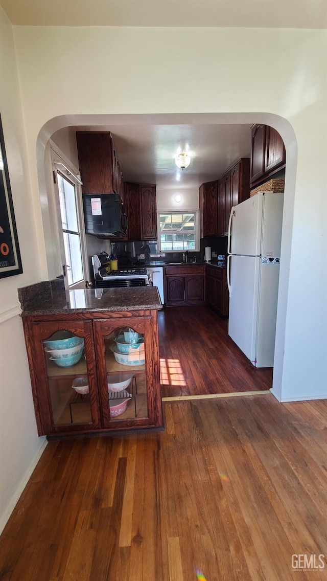 2617 4th St, Bakersfield, CA 93304 - kitchen with freestanding refrigerator, arched walkways, dark wood-style flooring, stainless steel range with gas stovetop, and dishwashing machine