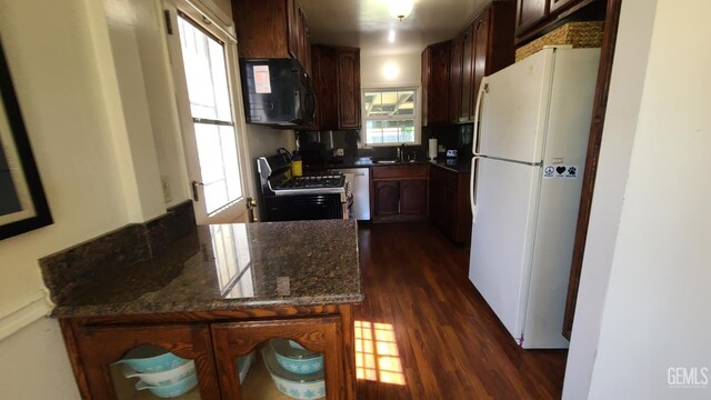 2617 4th St, Bakersfield, CA 93304 - kitchen with freestanding refrigerator, black microwave, stainless steel gas range oven, dark wood-style floors, and dark stone countertops