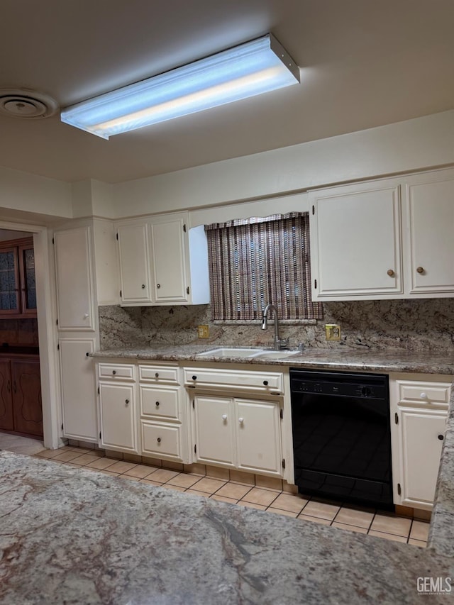 kitchen featuring sink, tasteful backsplash, light tile patterned floors, black dishwasher, and white cabinets