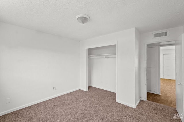 unfurnished bedroom with a textured ceiling, carpet floors, and a closet