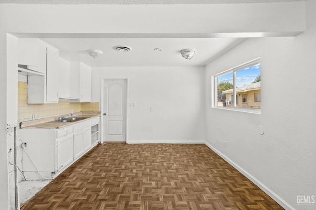 kitchen featuring dark parquet floors, tasteful backsplash, white cabinetry, and sink