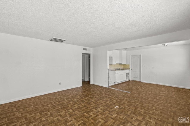 unfurnished living room featuring dark parquet floors and a textured ceiling