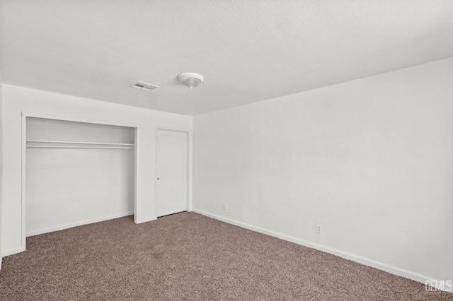 unfurnished bedroom featuring carpet floors, a textured ceiling, and a closet