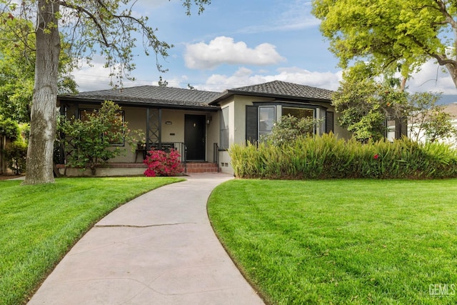3025 19th St, Bakersfield, CA 93301 - view of front of home with covered porch, stucco siding, and a front lawn