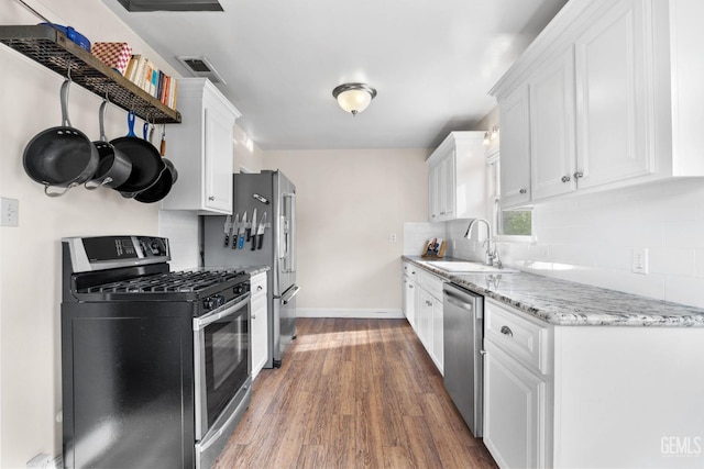 3025 19th St, Bakersfield, CA 93301 - kitchen with decorative backsplash, a sink, white cabinets, appliances with stainless steel finishes, and wood finished floors