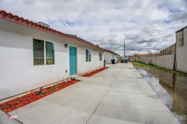 exterior space featuring stucco siding and fence