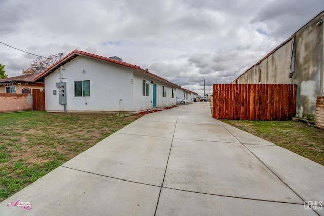 view of home's exterior featuring stucco siding, a tile roof, a yard, and fence