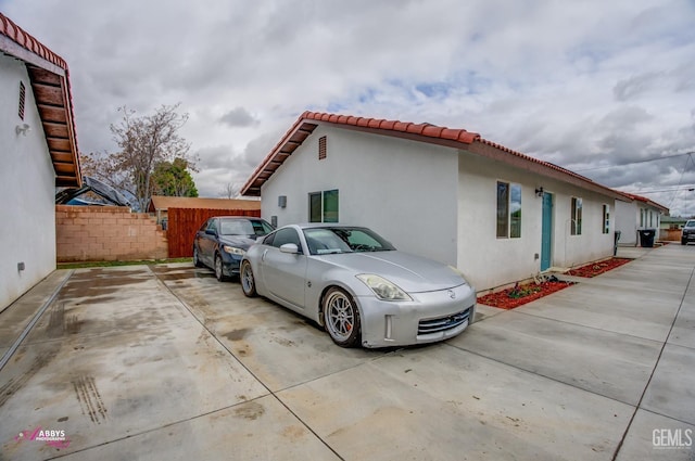 view of home's exterior with a tile roof, fence, and stucco siding