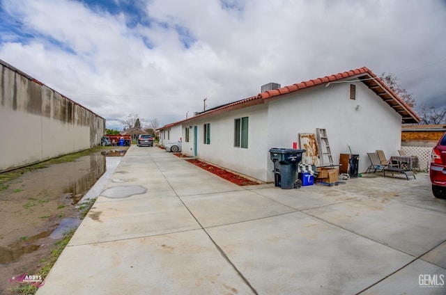 rear view of house with a patio, a tiled roof, fence, and stucco siding