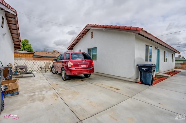view of side of property featuring a tiled roof, a patio area, and stucco siding