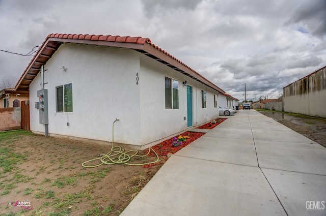 view of side of home with a patio area, fence, and stucco siding