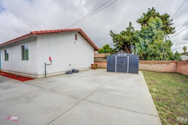 view of property exterior with a storage shed, an outbuilding, fence, and a patio