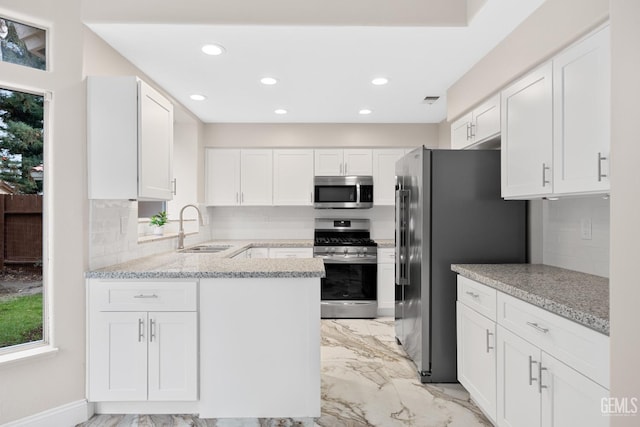 kitchen featuring white cabinetry, sink, stainless steel appliances, and light stone counters