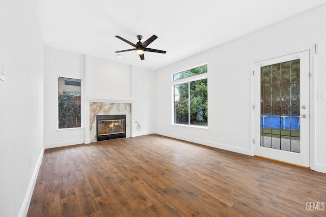 unfurnished living room with a premium fireplace, ceiling fan, and dark hardwood / wood-style floors