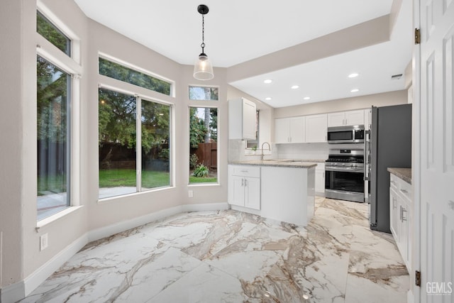 kitchen with white cabinets, decorative backsplash, decorative light fixtures, light stone counters, and stainless steel appliances