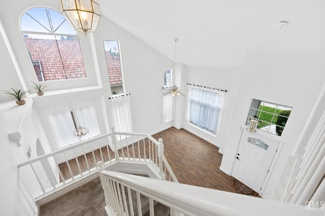 staircase with ceiling fan with notable chandelier and vaulted ceiling