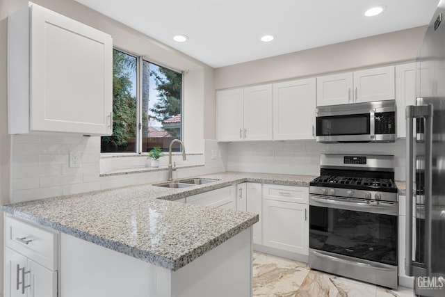 kitchen featuring light stone countertops, stainless steel appliances, white cabinetry, and sink