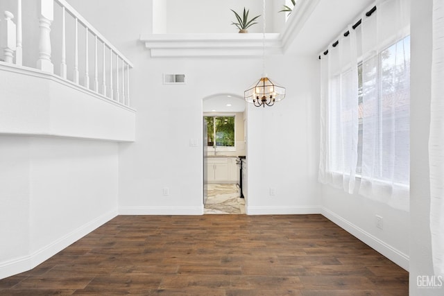 spare room featuring dark hardwood / wood-style flooring and a chandelier