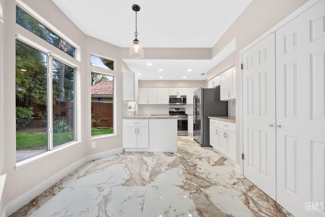 kitchen with sink, stainless steel appliances, light stone counters, pendant lighting, and white cabinets