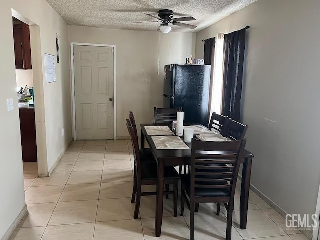 dining space with light tile patterned floors, baseboards, ceiling fan, and a textured ceiling