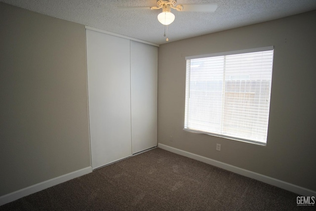 carpeted spare room with a textured ceiling, a ceiling fan, and baseboards