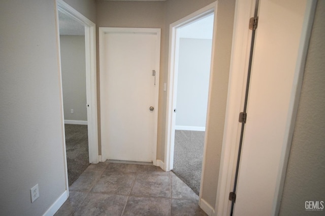 corridor with baseboards and light colored carpet