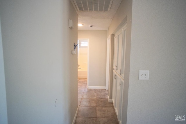 corridor with visible vents, baseboards, and light tile patterned floors