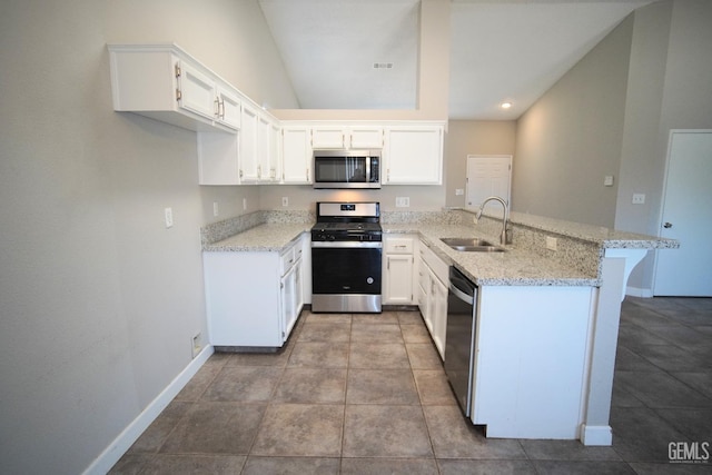 kitchen featuring light stone counters, stainless steel appliances, white cabinetry, a sink, and a peninsula