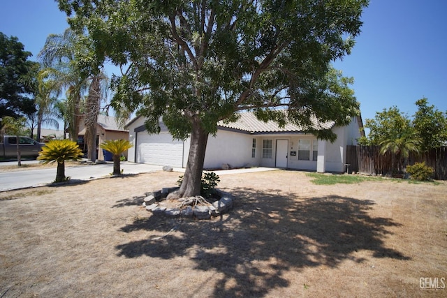 ranch-style home with an attached garage, fence, concrete driveway, and stucco siding