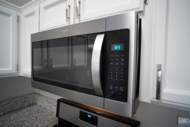 room details featuring light stone countertops, white cabinetry, stainless steel microwave, and oven