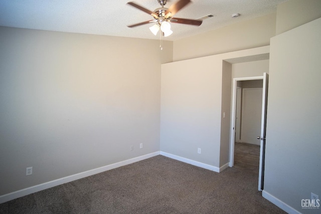 empty room with dark colored carpet, visible vents, a ceiling fan, a textured ceiling, and baseboards