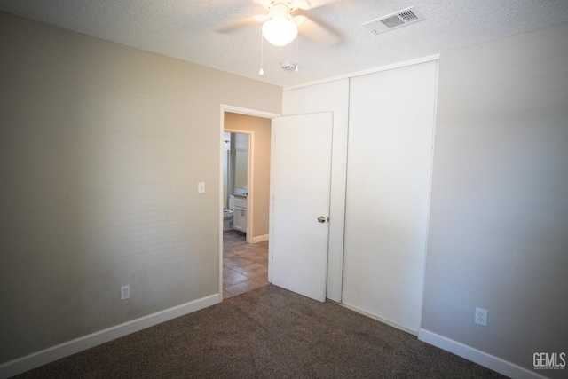 unfurnished bedroom with a closet, light colored carpet, visible vents, a textured ceiling, and baseboards