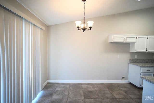 unfurnished dining area featuring baseboards and a notable chandelier