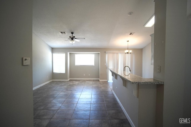 interior space with baseboards, visible vents, a textured ceiling, and ceiling fan with notable chandelier