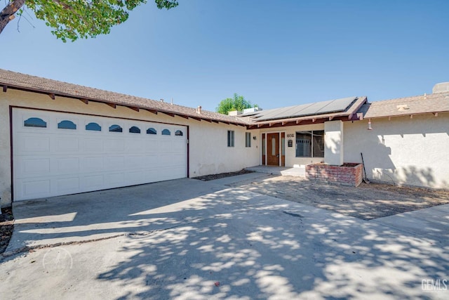 single story home with a garage and solar panels