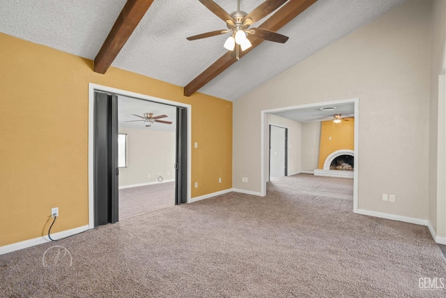 carpeted spare room with ceiling fan, vaulted ceiling with beams, a textured ceiling, and a fireplace