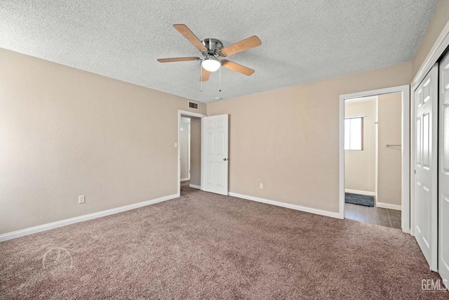 unfurnished bedroom featuring ensuite bathroom, ceiling fan, light carpet, a textured ceiling, and a closet